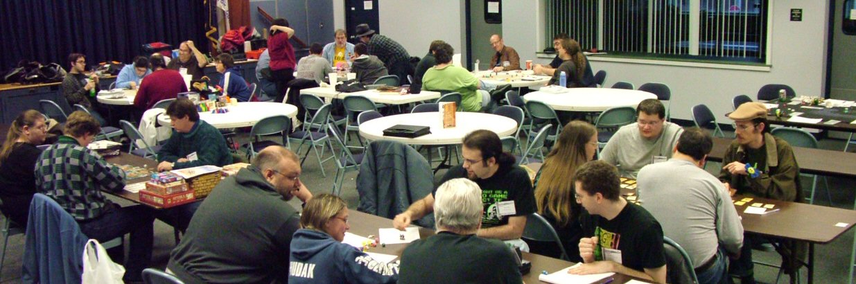 Foreground Cthulhu by Author CJ Henderson, Right is Erica running Munchkins!, Left is Jasmine running a Boardgame and background is The Regulators D&D Group with three tables running.